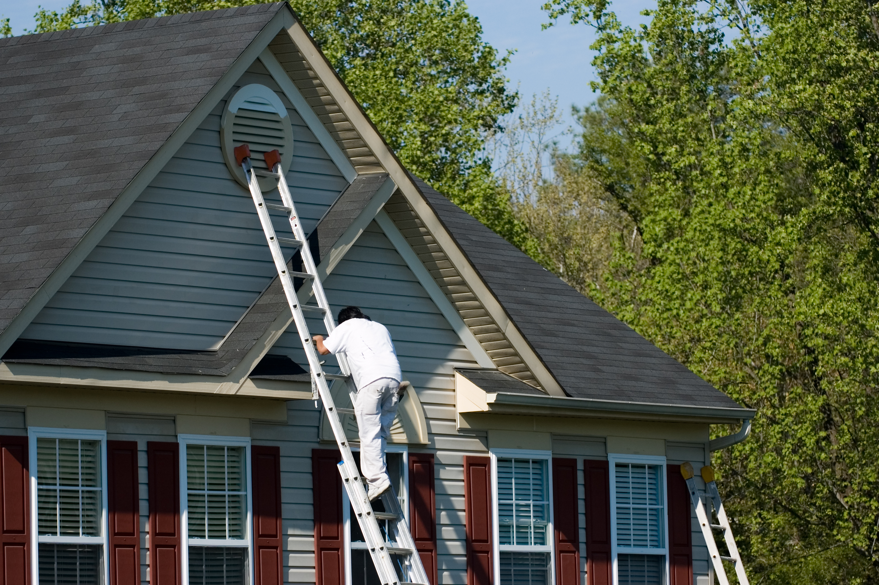 A painter coming down a ladder with a bucket of paint